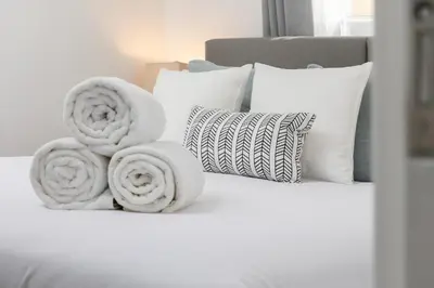 a white bed with pillows and towels on it at 3 Bedroom House - Fire Pit Table BBQ - 10 Guests in La Mesa