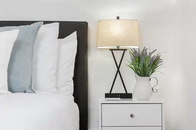 a bedroom with a bed with a lamp and a vase with flowers at 2 Bedroom - Ocean View Hot Tub Parking - 8 Guest in San Diego