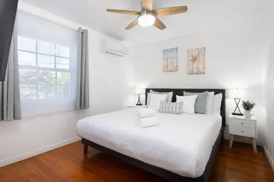 a white bedroom with a large bed and a ceiling fan at 2 Bedroom - Ocean View Hot Tub Parking - 8 Guest in San Diego