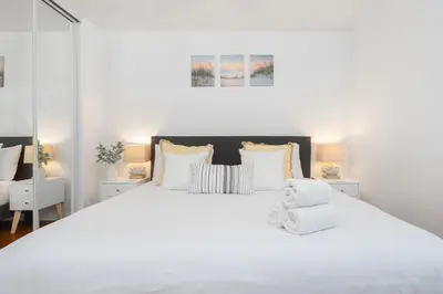 a white bedroom with a large bed with white pillows at 2 Bedroom - Ocean View Hot Tub Parking - 8 Guest in San Diego