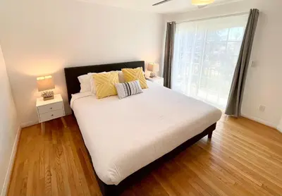 a bedroom with a bed with white sheets and yellow pillows at Hidden Gem with Hot Tub and Parking - 4 Guests in San Diego