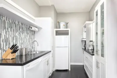 a white kitchen with a sink and a refrigerator at Inn at the Park: San Diego Suites in San Diego