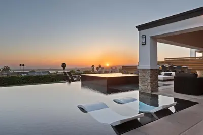 a pool with chairs and a sunset in the background at Panoramic Ocean sunset Views with Heated Pool & Spa best location in San Diego