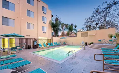 a swimming pool with blue chairs and a building at San Diego - Mission Valley Condos in San Diego