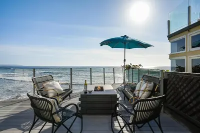 a patio with chairs and a table and an umbrella at Luxury, renovated, oceanfront home with incredible deck & views - dogs welcome in San Diego