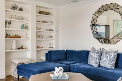 a living room with a blue couch and a mirror at Luxury, renovated, oceanfront home with incredible deck & views - dogs welcome in San Diego
