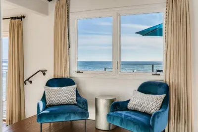two blue chairs in front of a window with the ocean at Luxury, renovated, oceanfront home with incredible deck & views - dogs welcome in San Diego