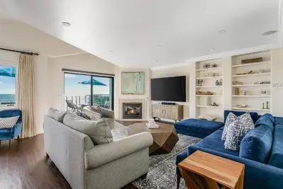 a living room with a blue couch and a tv at Luxury, renovated, oceanfront home with incredible deck & views - dogs welcome in San Diego