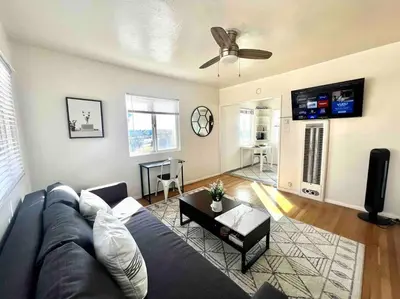 a living room with a blue couch and a flat screen tv at Minimalist 1 bed by Airport & Old Town in San Diego