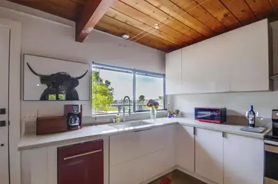 a kitchen with white cabinets and a large window at Avoyer One Bedroom Guesthouse - La Mesa in La Mesa