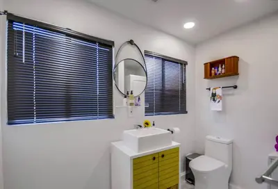 a bathroom with a sink and a mirror and a toilet at Avoyer One Bedroom Guesthouse - La Mesa in La Mesa