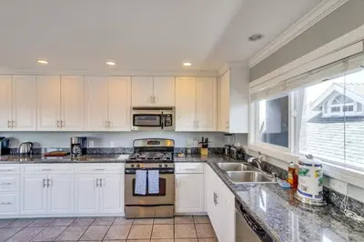 a kitchen with white cabinets and a stove and a sink at Mission Beach Townhome Getaway in San Diego