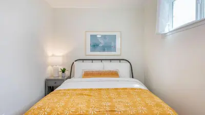 a white bedroom with a bed with an orange blanket at Surfrider I by AvantStay Walk to the Beach Patio in Newport Beach
