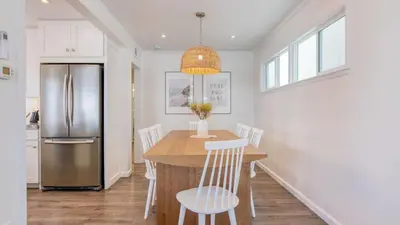 a kitchen with a table with chairs and a refrigerator at Surfrider I by AvantStay Walk to the Beach Patio in Newport Beach
