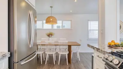 a kitchen with a table with chairs and a refrigerator at Surfrider I by AvantStay Walk to the Beach Patio in Newport Beach