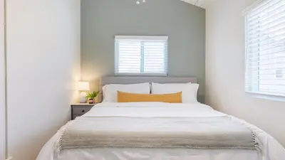 a bedroom with a large white bed with an orange pillow at Surfrider II by AvantStay Walk to the Beach Balcony in Newport Beach