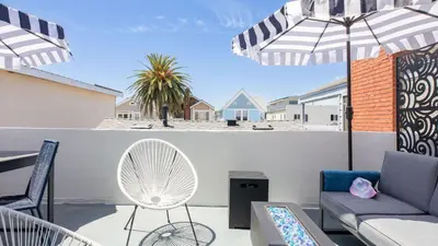 a patio with a couch and chairs and an umbrella at Surfrider II by AvantStay Walk to the Beach Balcony in Newport Beach