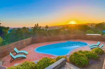 a swimming pool with a sunset in the background at The Helix House - Pool & Mountain Views in La Mesa