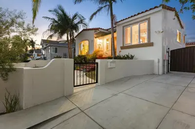 a white house with a fence and palm trees at La Playa - Charming Bayside Bungalow in San Diego