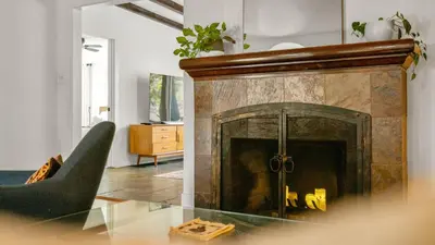 a living room with a fireplace and a chair at Chic Kensington Home - Hot Tub & Canyon Views in San Diego