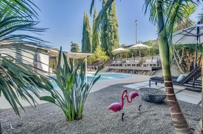 two pink flamingos on gravel next to a swimming pool at Agua Dulce - Mid Century Oasis - Pool &Hot Tub in Spring Valley