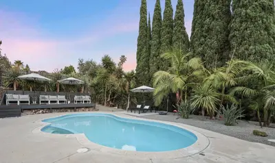 a swimming pool in a yard with palm trees at Agua Dulce - Mid Century Oasis - Pool &Hot Tub in Spring Valley