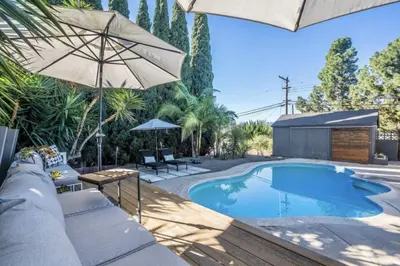 a swimming pool with an umbrella and some chairs and tables at Agua Dulce - Mid Century Oasis - Pool &Hot Tub in Spring Valley