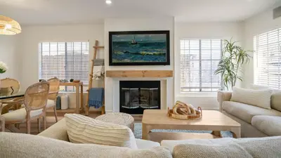 a living room with a fireplace with a tv above it at The Oliver - Pacific Beach Hideaway in San Diego