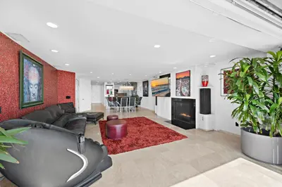 a living room with a black couch and a red wall at 3 Story Oceanfront Home with Jacuzzi in Newport Beach on the Sand! in Newport Beach