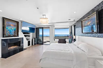 a bedroom with a large bed and a fireplace at 3 Story Oceanfront Home with Jacuzzi in Newport Beach on the Sand! in Newport Beach