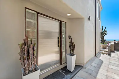 a house with two cactuses in front of a door at 3 Story Oceanfront Home with Jacuzzi in Newport Beach on the Sand! in Newport Beach