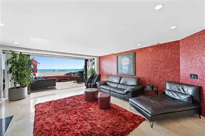 a living room with a couch and a red wall at 3 Story Oceanfront Home with Jacuzzi in Newport Beach on the Sand! in Newport Beach