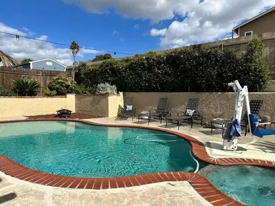 a large swimming pool with chairs and a patio at HC Accessible 4 Bed 3 Bath with Sparkling Pool and Spa-we have lifts and roll in shower in Santee
