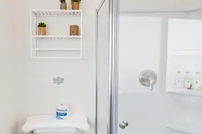 a white bathroom with a shower and a toilet at Cardiff Retreat with Game Room and Deck, Near Beach in Cardiff-by-the-Sea