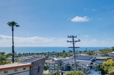 a view of a city with a palm tree and the ocean at Cardiff Retreat with Game Room and Deck, Near Beach in Cardiff-by-the-Sea