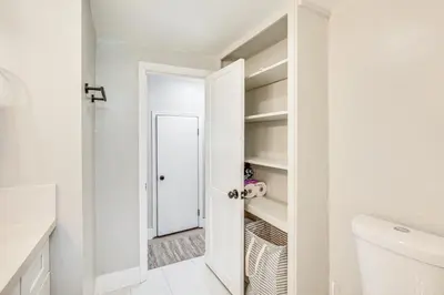 a white bathroom with a door to a closet at San Diego Apartment with Patio - Near Balboa Park! in San Diego