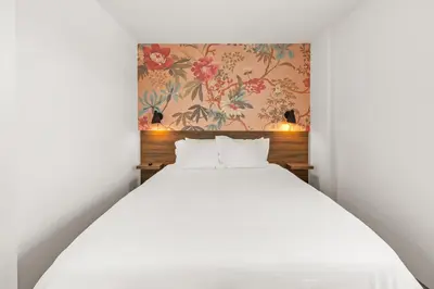 a bedroom with a white bed and a floral wallpaper at Uptown Inn - Limited Service Apart-Hotel in San Diego