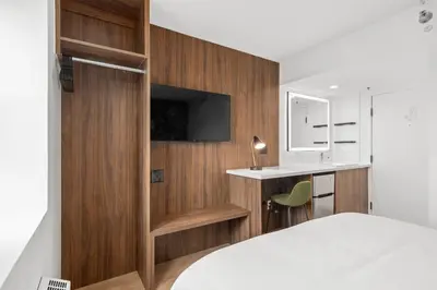 a bedroom with wood paneling and a bed and a desk at Uptown Inn - Limited Service Apart-Hotel in San Diego
