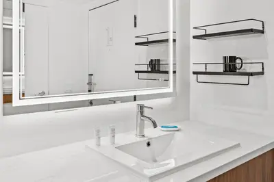 a white bathroom with a sink and a mirror at Uptown Inn - Limited Service Apart-Hotel in San Diego