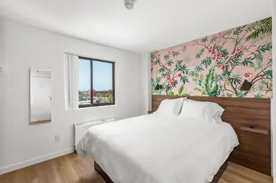 a white bedroom with a large bed with a floral wallpaper at Uptown Inn - Limited Service Apart-Hotel in San Diego
