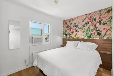 a bedroom with a white bed with a floral wallpaper at Uptown Inn - Limited Service Apart-Hotel in San Diego