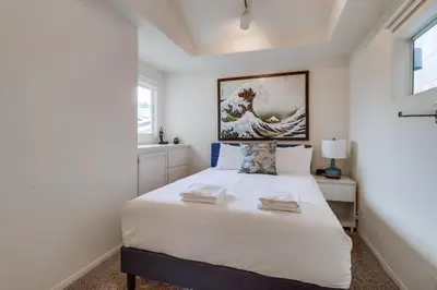 a bedroom with a white bed with a picture on the wall at Ocean & Bay Views Pool & Hot Tub Rooftop Patio in San Diego