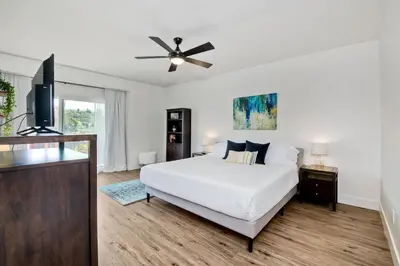 a white bedroom with a bed and a ceiling fan at Beautifully Remodeled - Private Balcony - Pool View - BBQ Access - Gated Reserved Parking in Encinitas