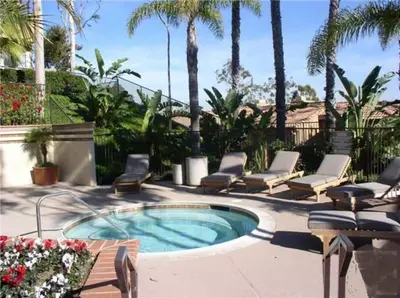 a patio with a pool and chairs and palm trees at Laguna Condo w/ Pool/Jacuzzi and Attached Garage in Laguna Niguel