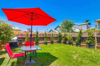 a red umbrella and two chairs and a table in a yard at California Cottage near SDSU in San Diego