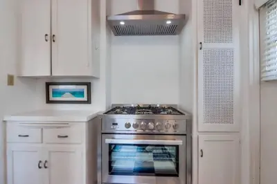 a kitchen with a stove and white cabinets at California Cottage near SDSU in San Diego