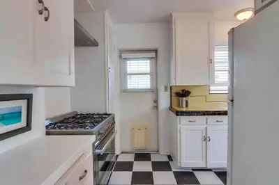 a kitchen with white cabinets and a black and white checkered floor at California Cottage near SDSU in San Diego