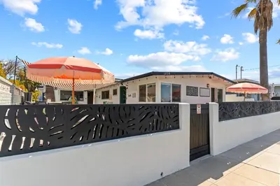 a fence with an umbrella in front of a restaurant at Beach Meets Fabulous at Oside Palms in Oceanside