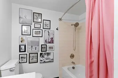 a bathroom with a pink shower curtain and pictures on the wall at Beach Meets Fabulous at Oside Palms in Oceanside