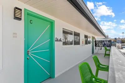 a green door on a building with green chairs at California Dreamin at O'side Palms in Oceanside